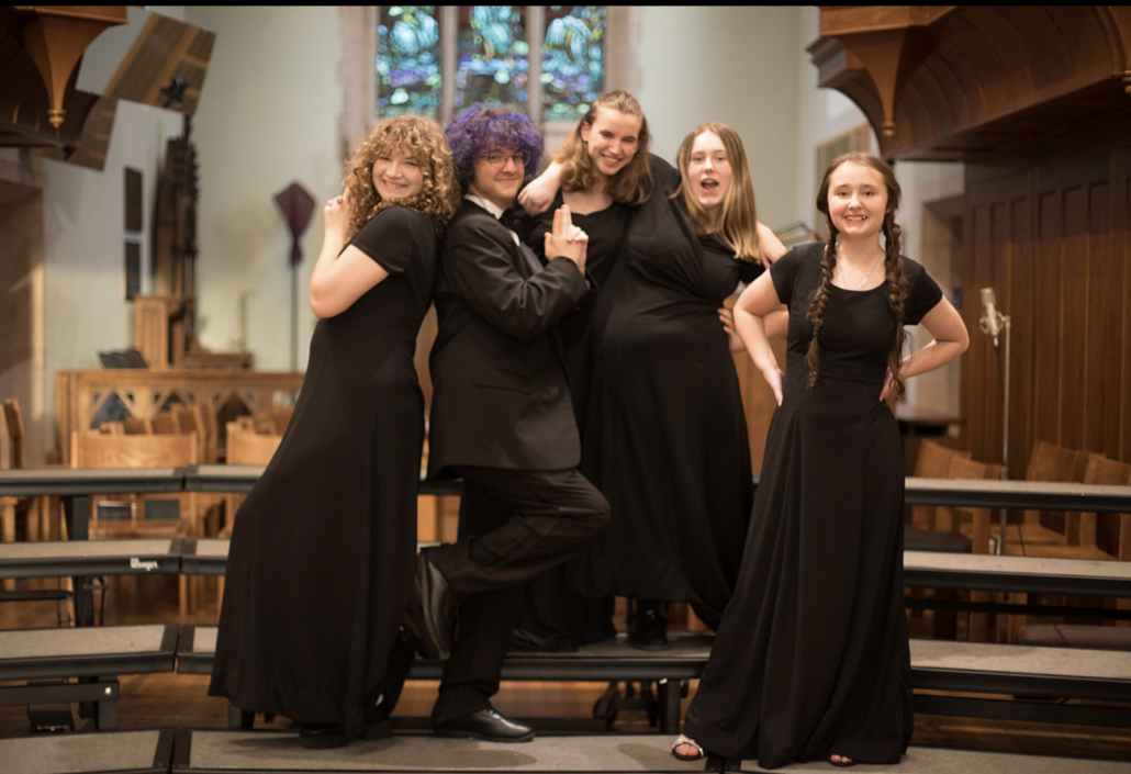 silly group photo with five singers on risers